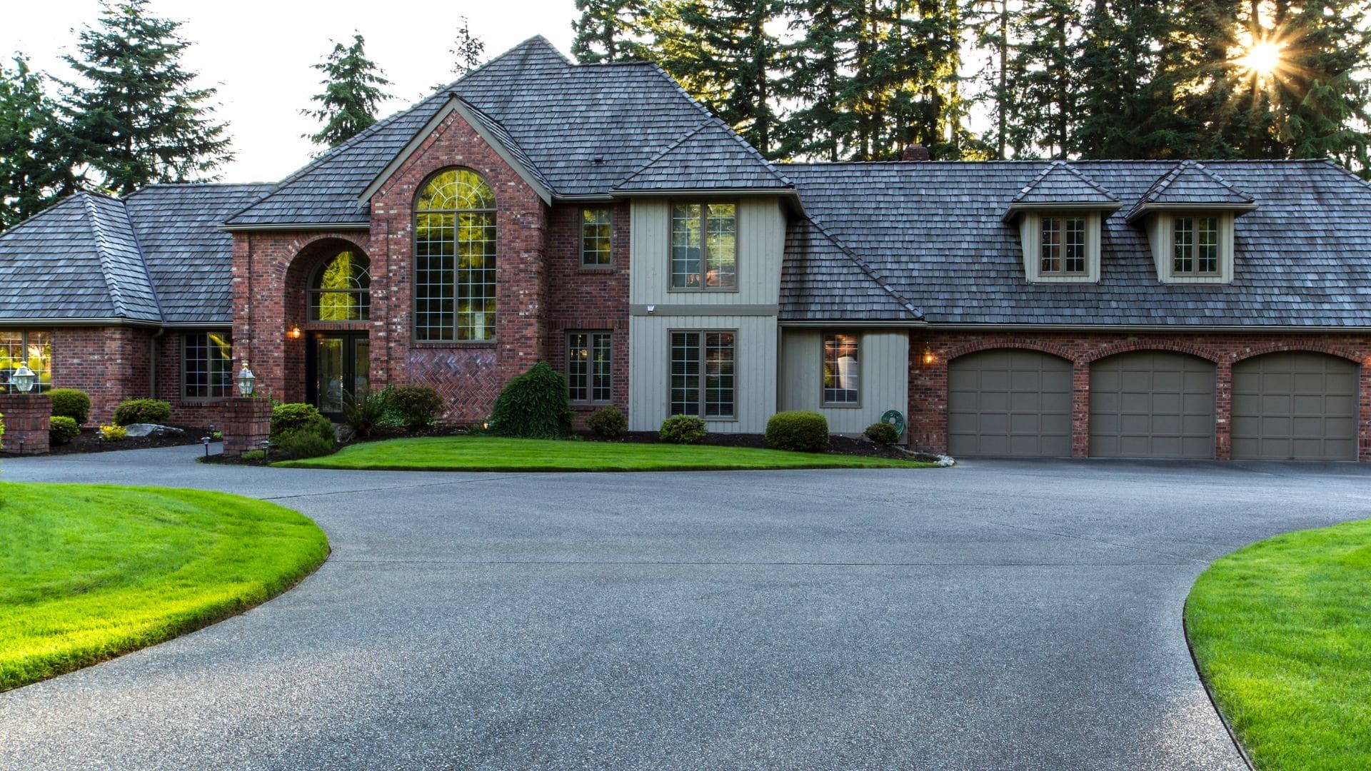 Brick estate home with three grey raised-panel garage doors