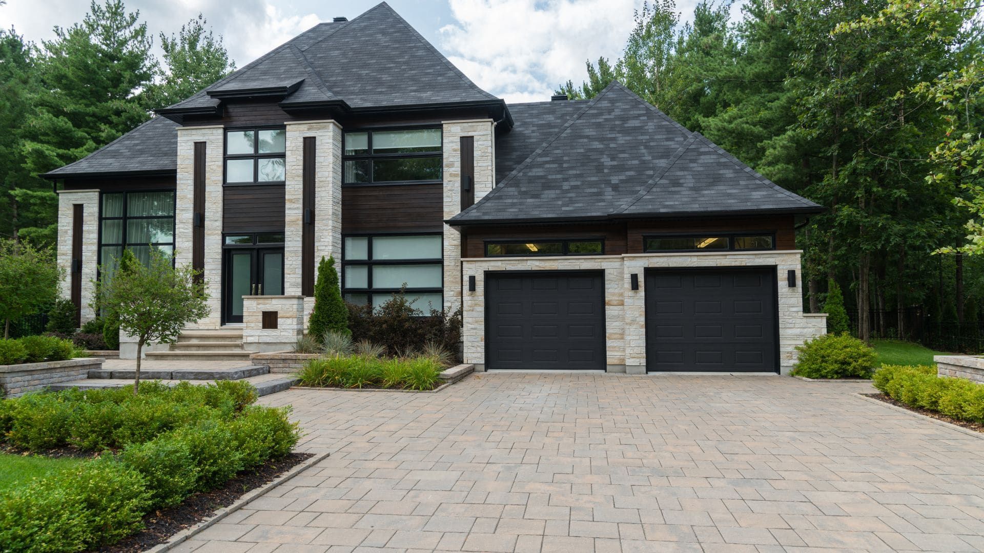 Stone-accented home with two black raised-panel garage doors