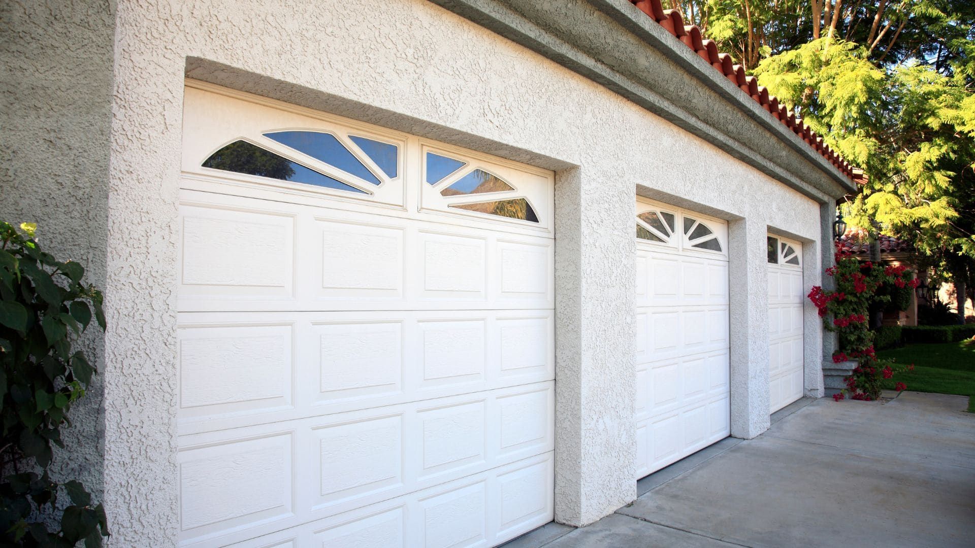 Stucco home with three white garage doors with sunburst windows