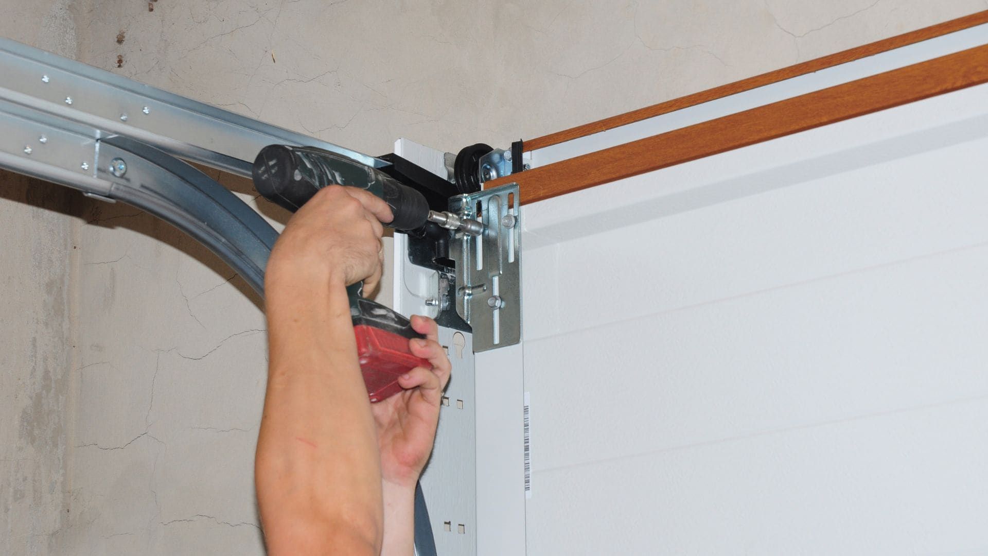 Installer fastening garage door track and roller brackets during installation