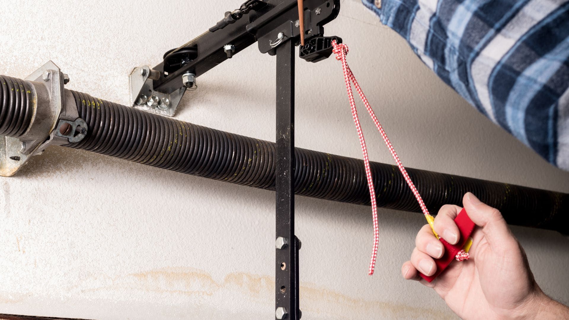 Technician replacing a garage door torsion spring above the door opening